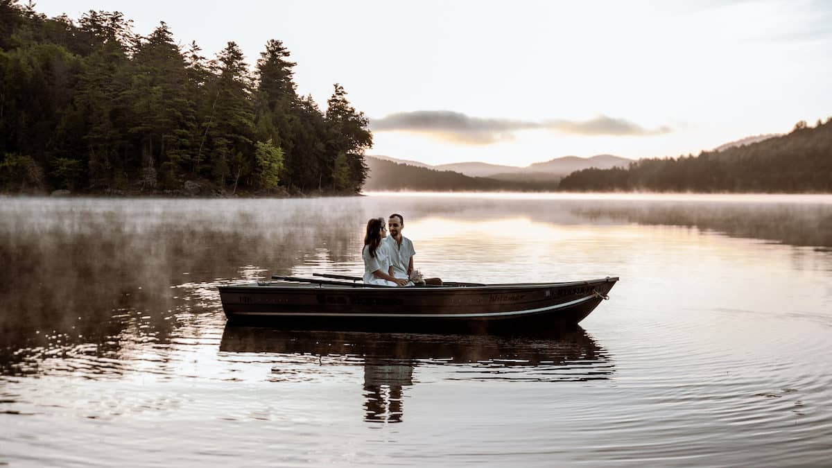 Couple eloping on Paradox Lake near Schroon Lake, New York at sunrise in a row boat