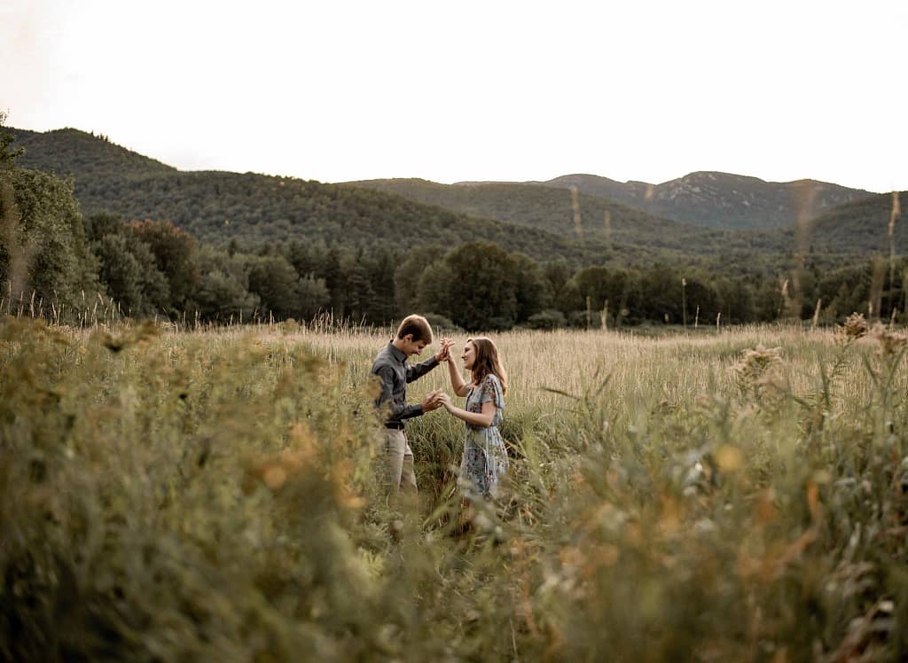Engagement photos in a field near the high peaks of the ADKs