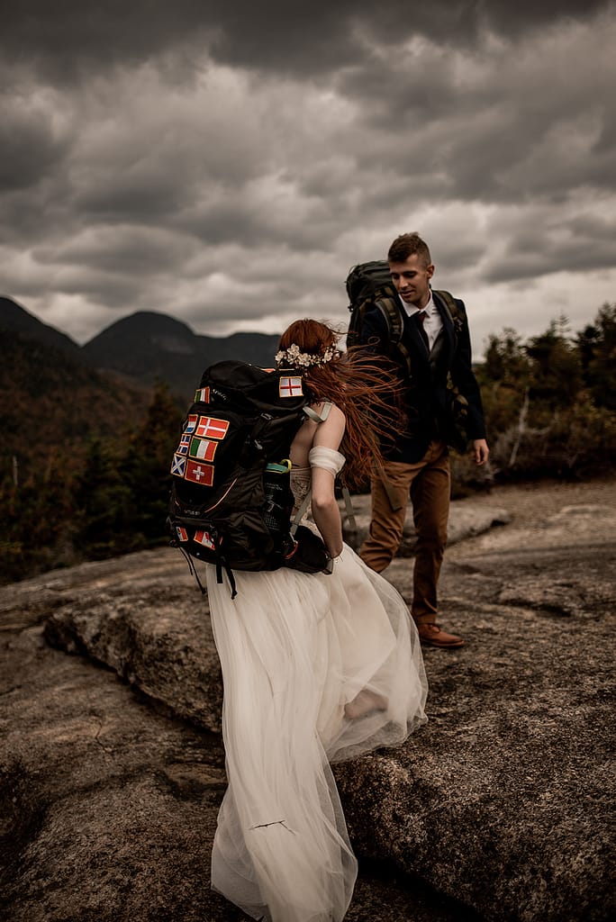 Bride and groom hiking in backpacks for a mountaintop elopement