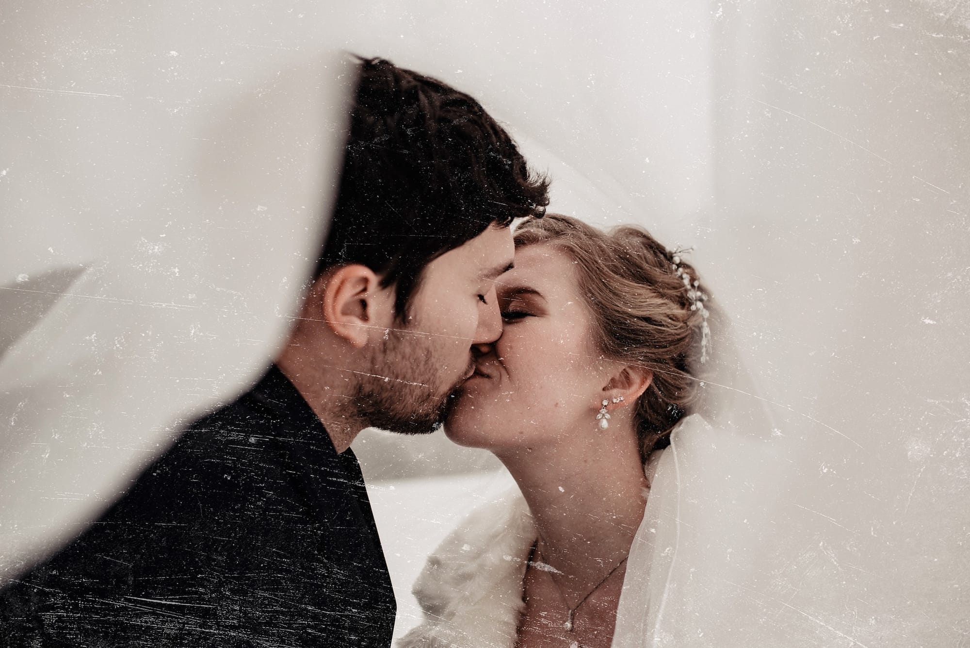 Photo of bride and groom kissing under the wedding veil